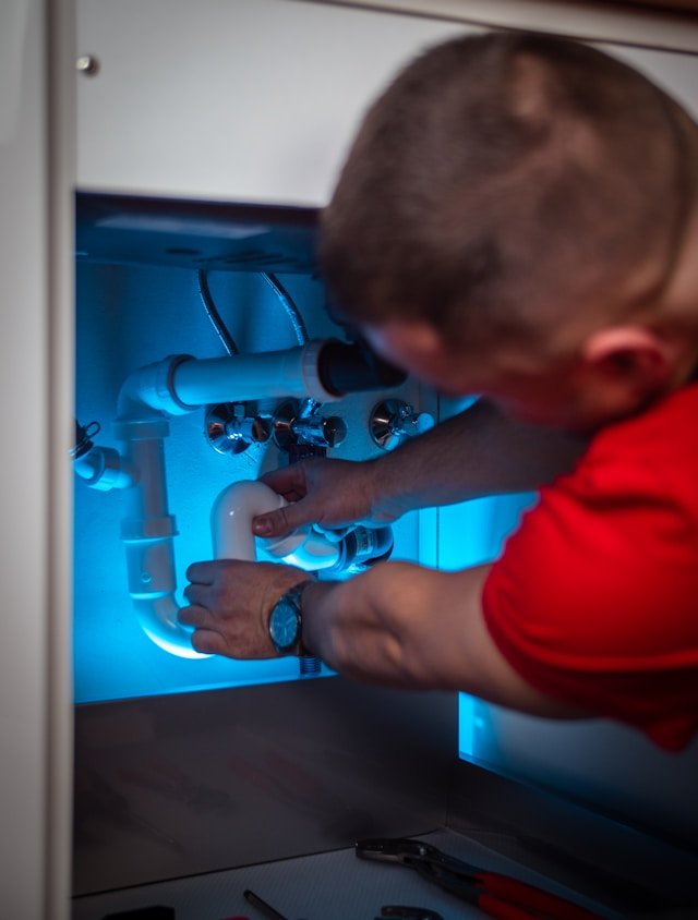 Plumber working under sink